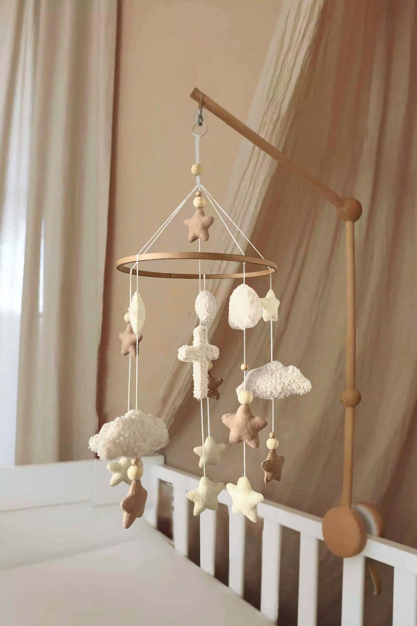 Nid d'ange mobile with stars and crosses, soft colors for a calming nursery atmosphere.