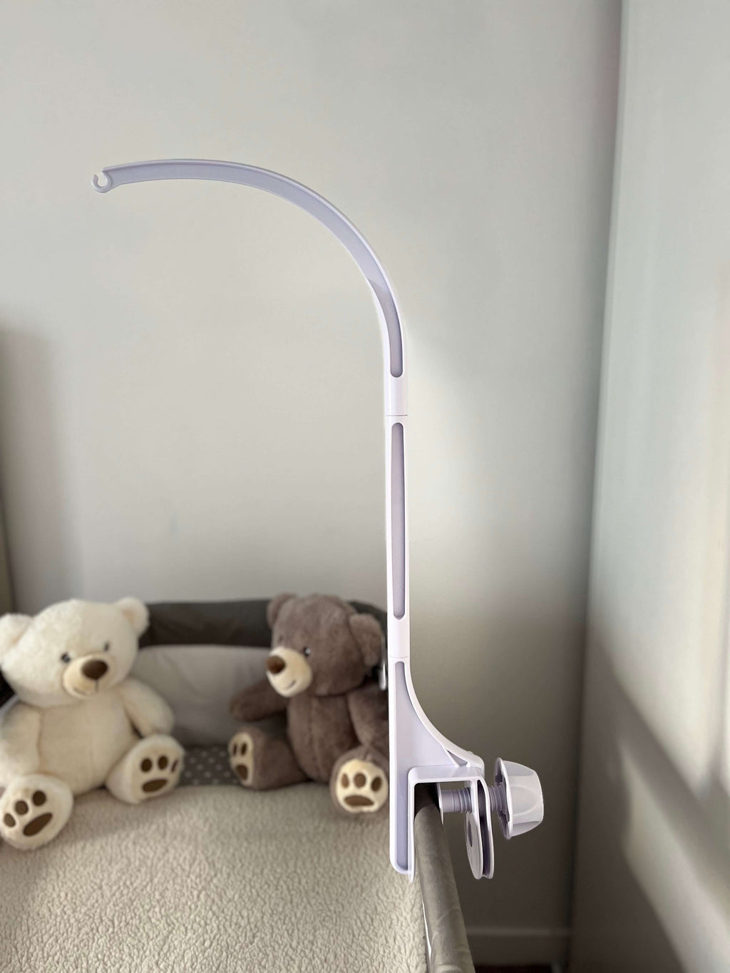 Support blanc pour mobile Béthléem, offrant un design apaisant près de deux ours en peluche dans un berceau.